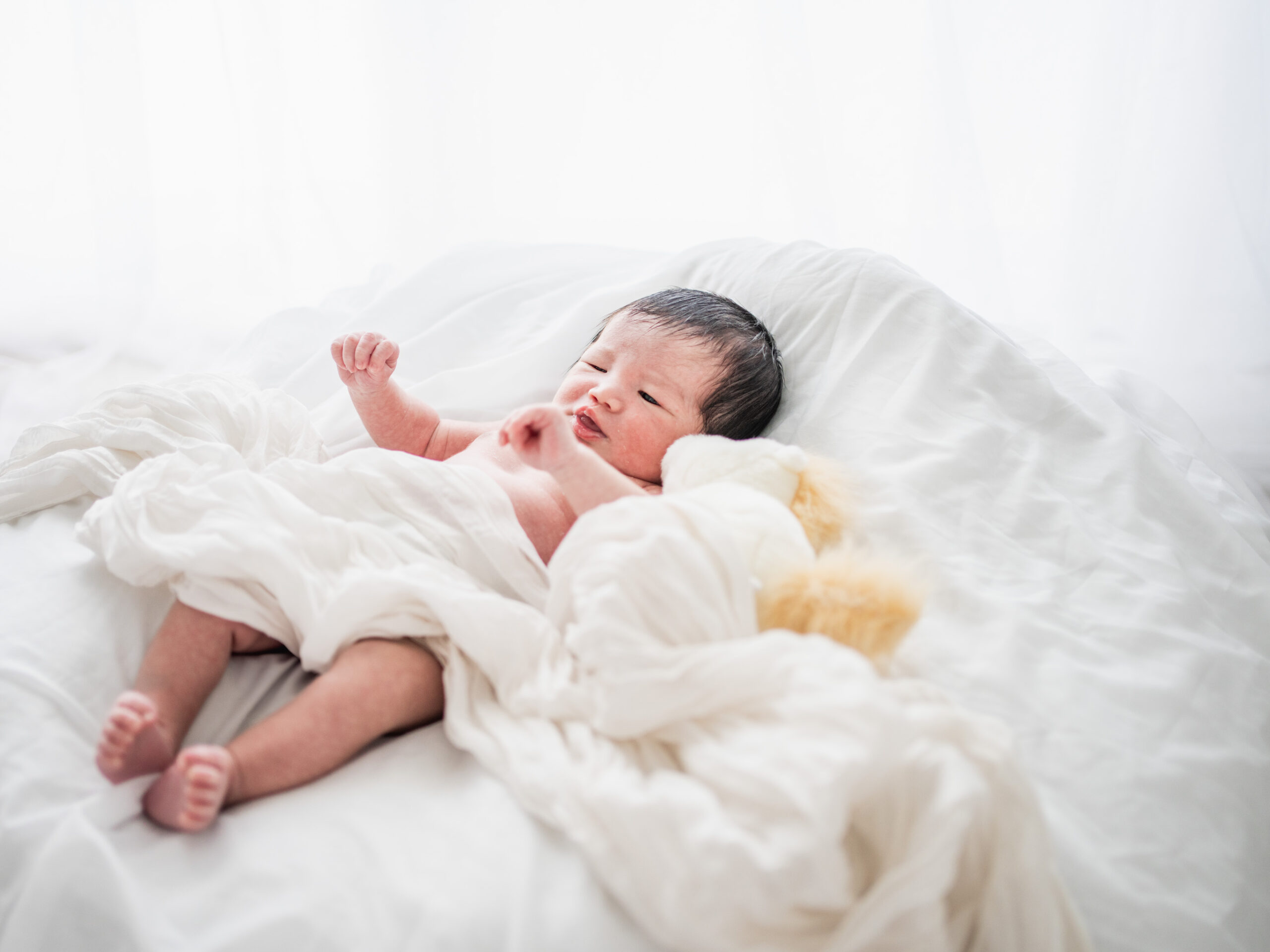 白いベッドの上で自然に過ごす新生児